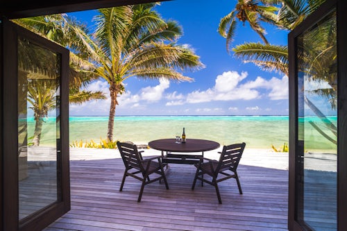 Cook Islands Landscape Travel Photography Luxury beachfront villa accommodation with sea views with champagne on a table next to tropical palm trees and the beautiful blue Pacific Ocean