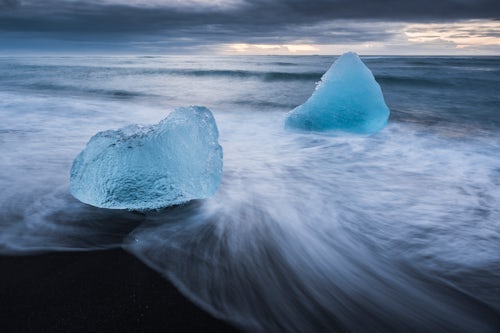 Iceland Landscape Photography Icebergs at sunrise melting due to climate change and global warming on Jokulsarlon Beach a black volcanic sand beach in South East Iceland Europe background with copy space