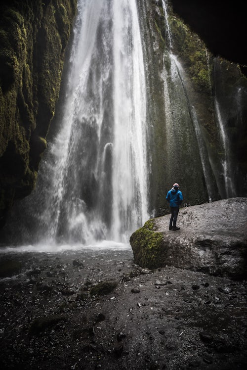 Iceland Travel Photography Tourist at the hidden Gljufrabui Waterfall near Seljalandsfoss South Iceland Sudurland