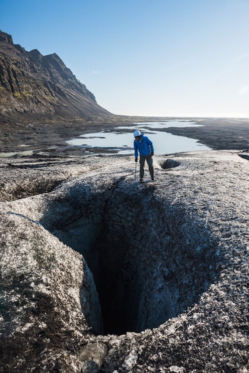 Iceland Travel Photography Tourist peering into a crevasse on Breidamerkurjokull Glacier Vatnajokull Ice Cap Iceland
