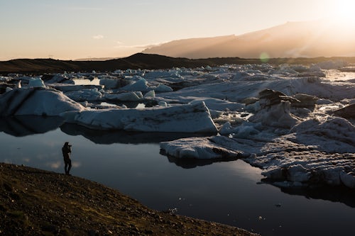 Iceland Travel Photography Tourist taking a photo of icebergs at Jokulsarlon Glacier Lagoon at sunset South East Iceland