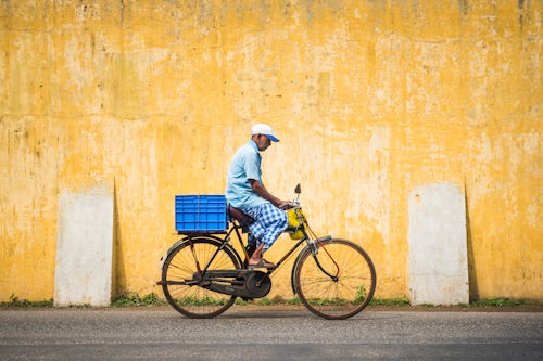 India Travel Street Photography Street scene of man on bicycle with yellow wall local life at Fort Kochi Cochin Kerala India