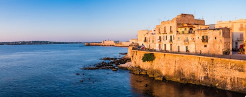 Italy Sicily Travel Photography Panoramic photo of Ortigia Old City at sunrise with Ortigia Castle Castello Maniace Castle Maniace in the background Syracuse Siracusa UNESCO World Heritage Site Sicily Italy Europe