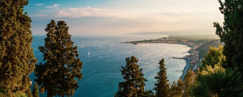 Italy Sicily Travel Photography Taormina on the Sicilian Coast at sunset panoramic photo of Naxos Bay with the foot on Mount Etna Volcano on the right Ionian Sea Mediterranean Sea Sicily Italy Europe
