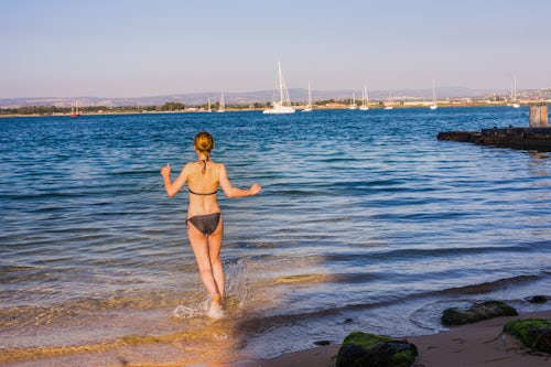 Italy Sicily Travel Photography Woman running into the Mediterranean Sea to go swimming at sunrise Ortigia Ortygia Syracuse Siracusa Sicily Italy Europe