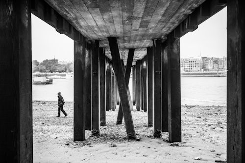 London Street Photography Walking on a River Thames beach underneath a pier on the banks of the River Thames South Bank London England