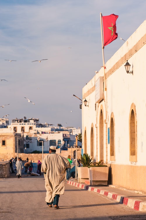 Morocco Travel Photography Moroccan man walking through Essaouira under the Moroccan flag to Moulay Assan Square Morocco North Africa Africa