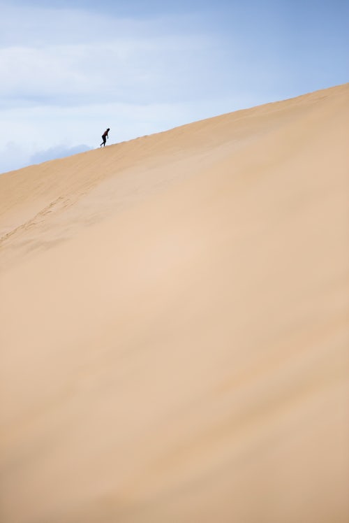 New Zealand Travel Photography Tourist climbing Te Paki Sand Dunes on 90 Mile Beach Northland New Zealand