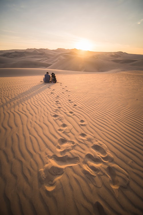 Peru Travel Photography Couple watching the sunset over sand dunes in the desert at Huacachina Ica Region Peru South America