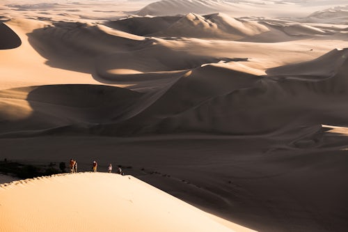 Peru Travel Photography People climbing sand dunes to watch the sunset over the desert at Huacachina Ica Region Peru South America